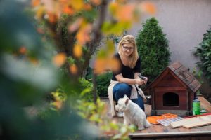 Femme en train de construire une niche pour son petit chien blanc dans le jardin